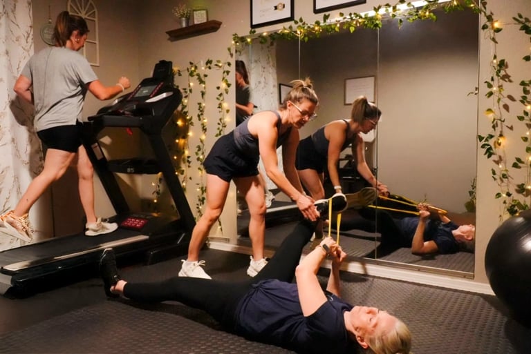 Group fitness class with people exercising using treadmill, kettlebell, and floor exercises in a modern gym decorated with greenery